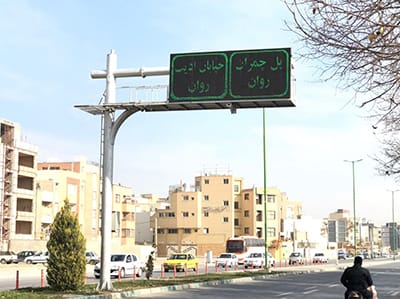 تابلو پیام متغیر (VMS) با نمایش پیام هشدار ترافیک و سرعت مجاز، نصبشده بر پایه فلزی کنار خیابان شهری